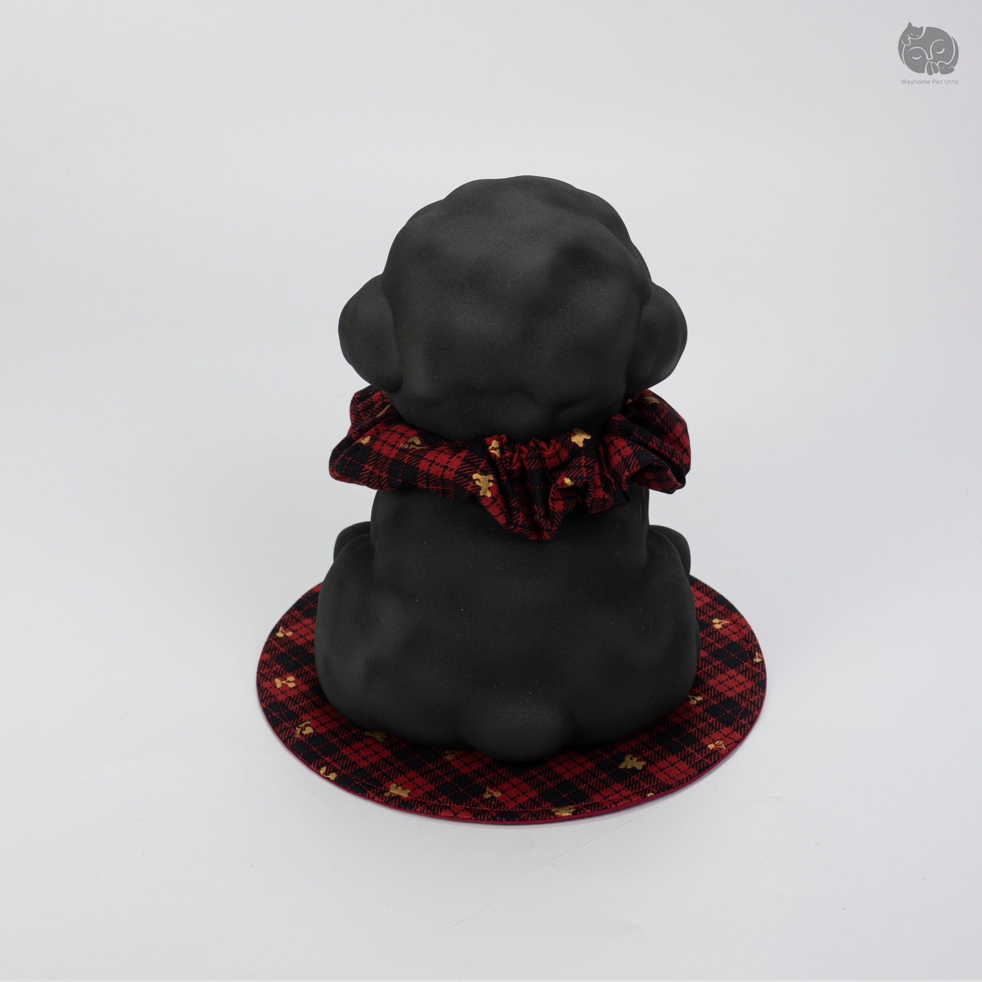 Top-down rear view of the black ceramic poodle urn on a decorative mat, showing the peaceful artisan design.