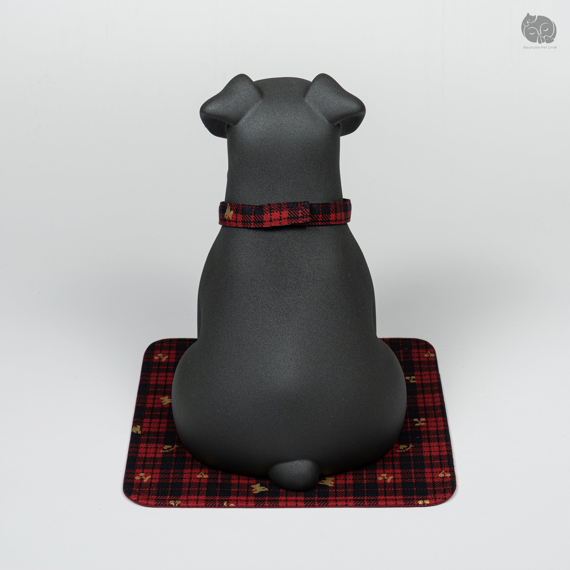 Rear view of the black ceramic Terrier urn on a decorative mat, showing the minimalist and sturdy design.